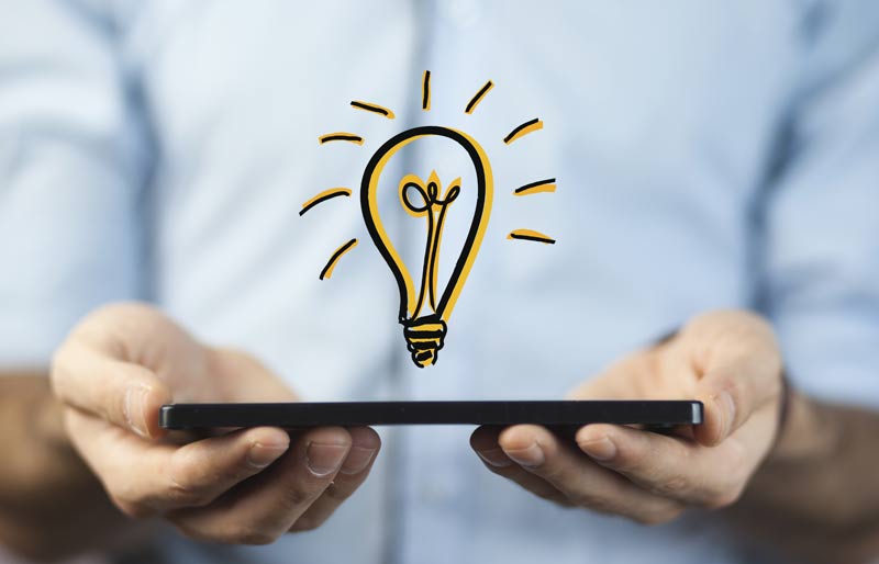 Businessman holding a tablet with a drawing of a light bulb hovering on top. 